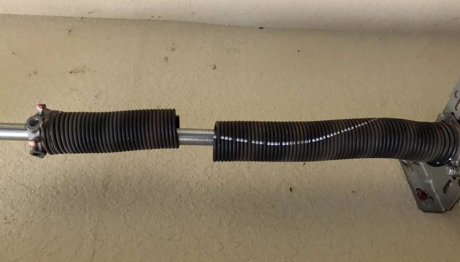a professional technician performing garage door spring repair on a residential garage, showcasing the tools and techniques used in Reynoldsburg Garage Door Repair services.